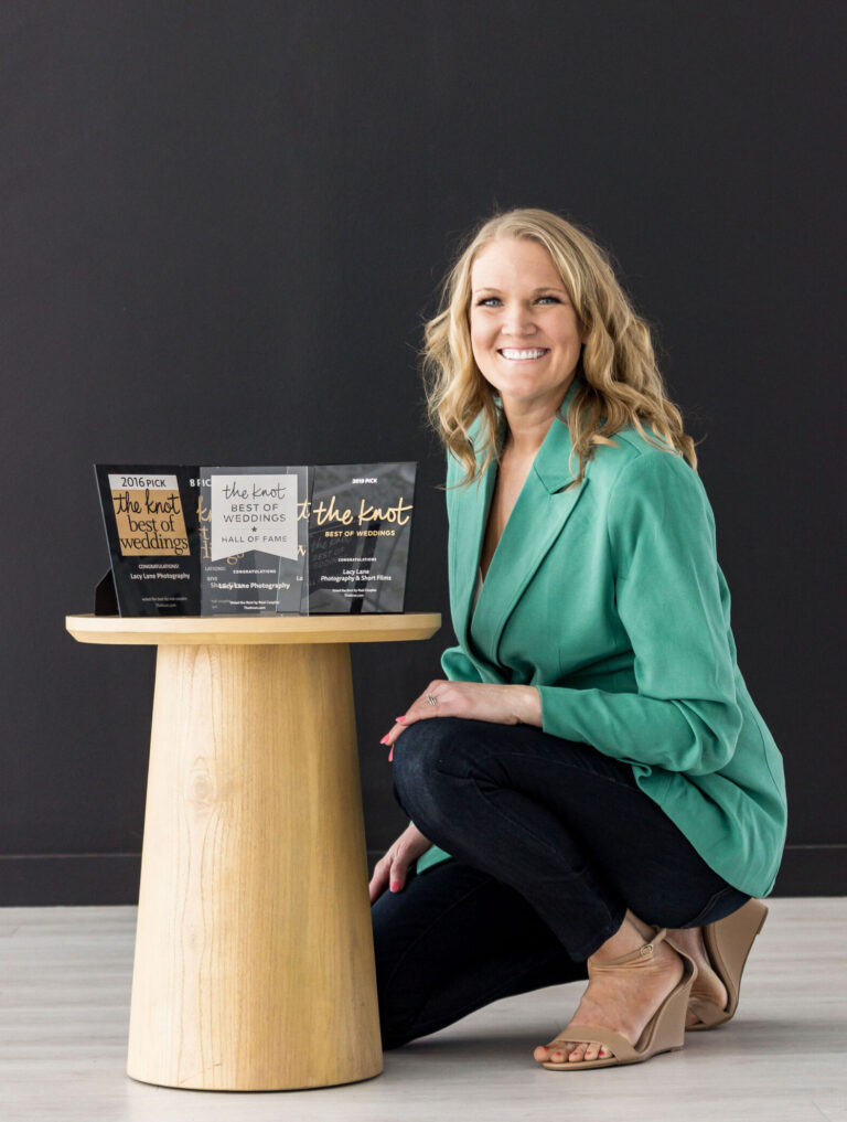 a woman sitting next to a table with books. Photo of Bushel + Peck Photo Founder and CEO.