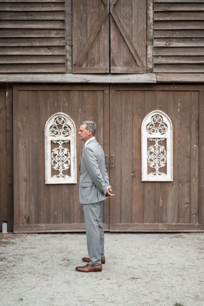 a man in a suit standing in front of a wooden building , 7 Must-Have Steps for the Ultimate Wedding Photography Poses Checklist