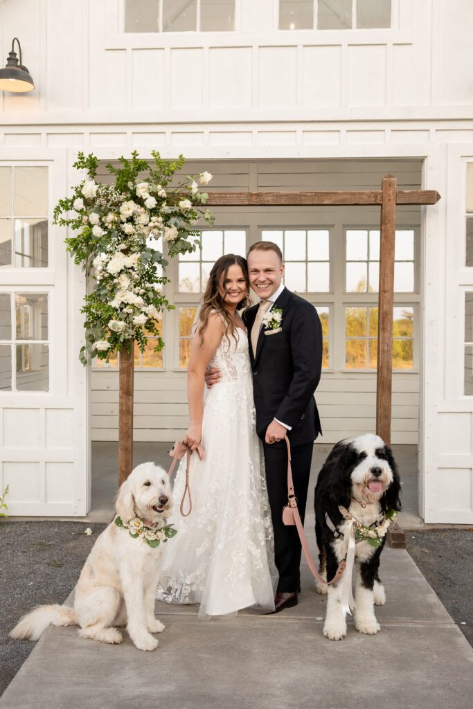 a man and woman standing next to two dogs , 8 Tips for Incorporating Pets into Your Wedding Photos