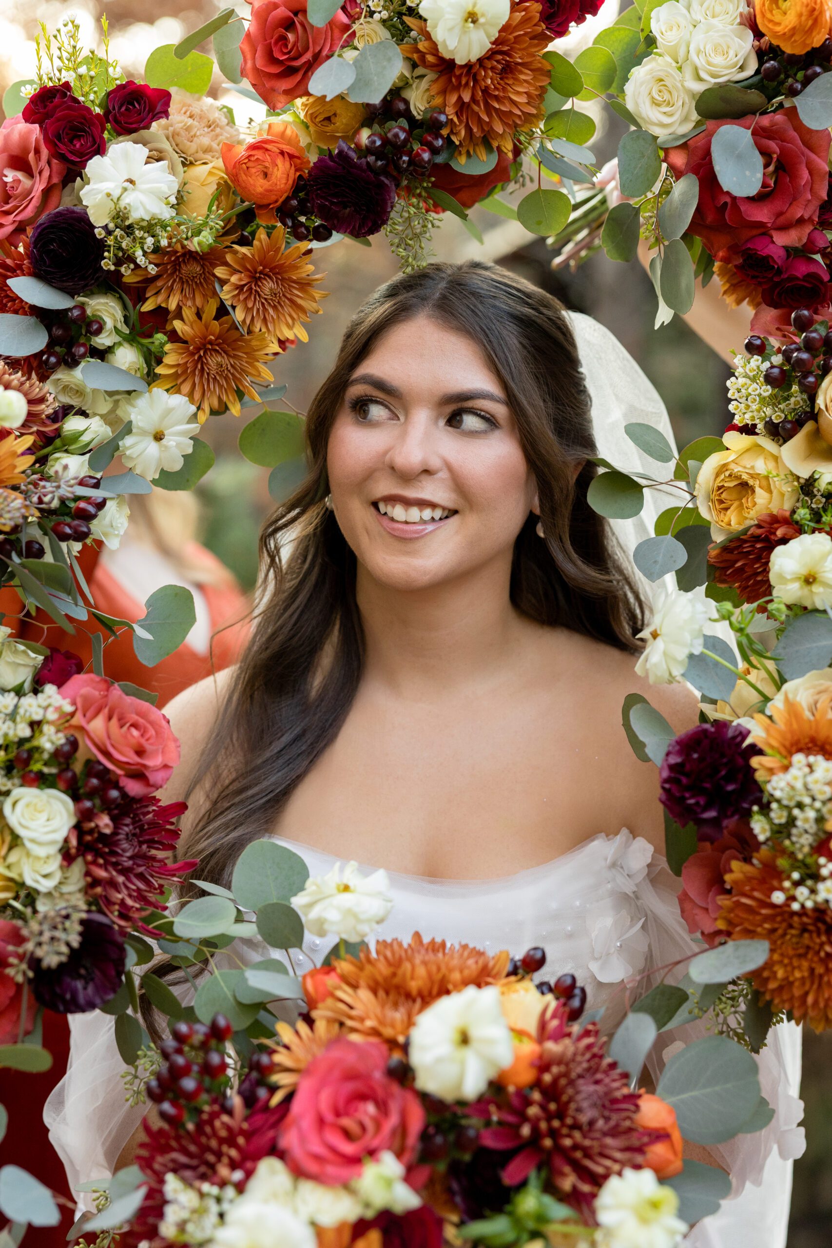 Bride framed in autumn jewel tone florals with burnt orange and burgundy at Avalon Legacy Ranch fall wedding in Texas photographed by Bushel + Peck Photo