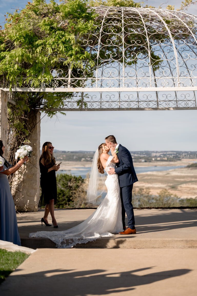Bride and groom sharing their first kiss during their wedding ceremony at Vintage Villas Hotel & Events in Austin Texas photographed by Austin wedding photographers Bushel + Peck Photo.