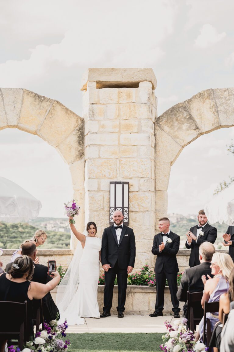 Bride standing beneath a stone arch with Hill Country views at La Cantera Resort in San Antonio photographed by Bushel + Peck Photo.