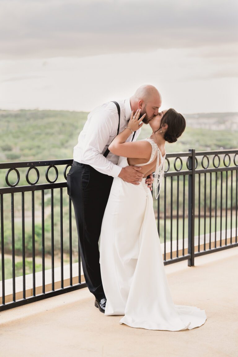 Bride and groom kissing on a balcony overlooking the Hill Country at La Cantera Resort in San Antonio photographed by Bushel + Peck Photoa