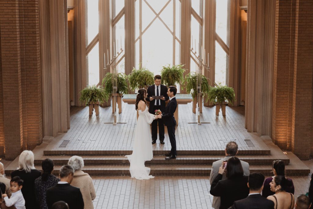 Bride and groom at the altar during their wedding ceremony at Marty Leonard Community Chapel in Fort Worth, captured by Bushel + Peck Photo