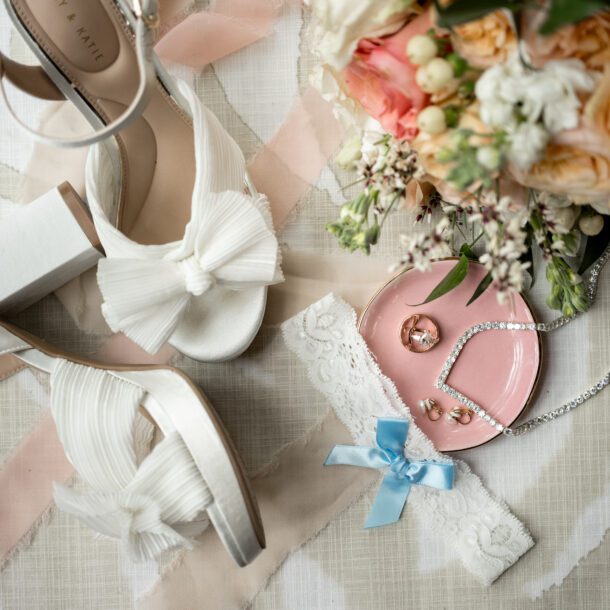 Wedding detail flat lay featuring bridal shoes, jewelry, and bouquet photographed by Bushel + Peck Photo.