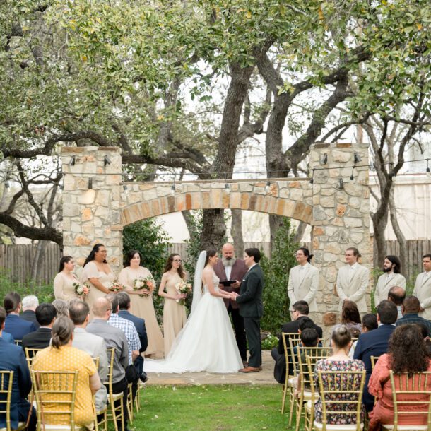 Outdoor wedding ceremony under a stone arch at The Veranda in San Antonio photographed by Bushel + Peck Photo.