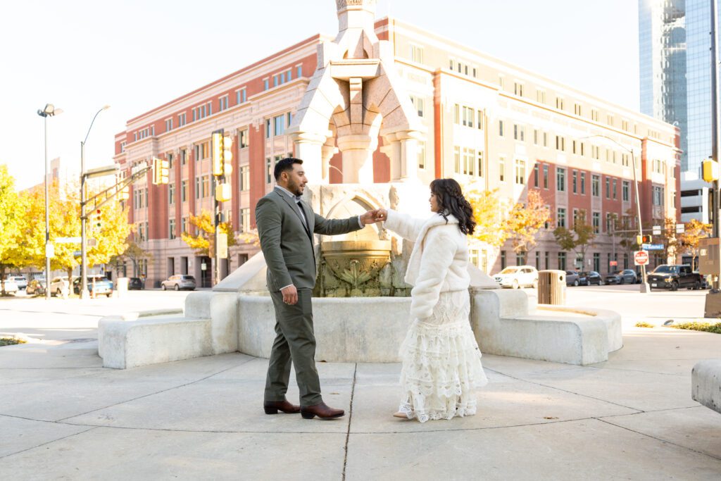 Couple beside the historic Horse Fountain in front of the Tarrant County Courthouse in Fort Worth, captured by Bushel + Peck Photo