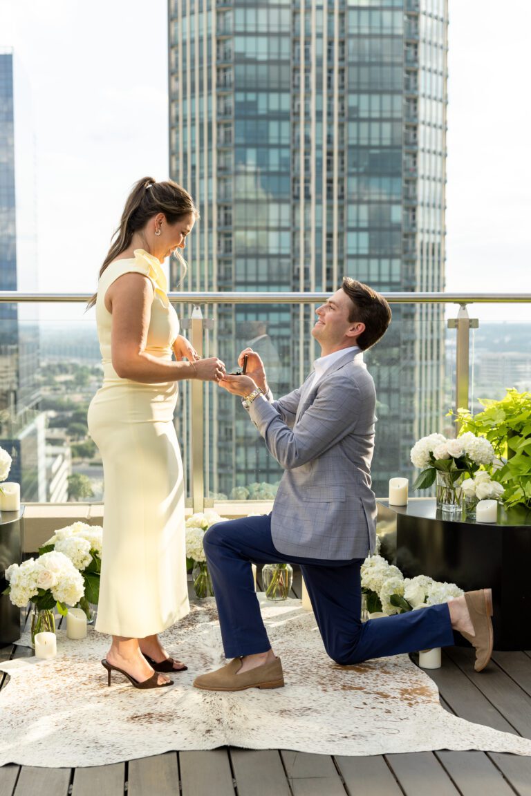 Rooftop proposal at The Sinclair Hotel in downtown Fort Worth, man on one knee proposing to woman with the skyline behind him, captured by Bushel + Peck Photo