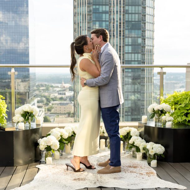 Couple kissing on the rooftop of The Sinclair Hotel with the downtown Fort Worth skyline, captured by Bushel + Peck Photo Fort Worth wedding photographers