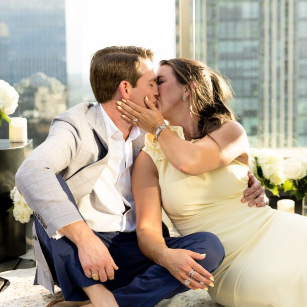 Couple kissing on the rooftop of The Sinclair Hotel after their proposal with the downtown Fort Worth skyline behind them, captured by Bushel + Peck Photo