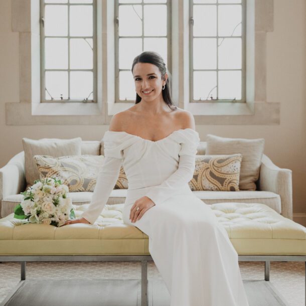 Bride seated on a tufted bench with her bouquet in the bridal suite at Highland Park United Methodist Church, captured by Bushel + Peck Photo