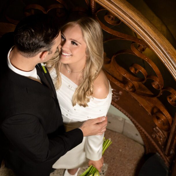 Overhead view of newlyweds embracing on the spiral staircase inside the Tarrant County Courthouse, captured by Bushel + Peck Photo