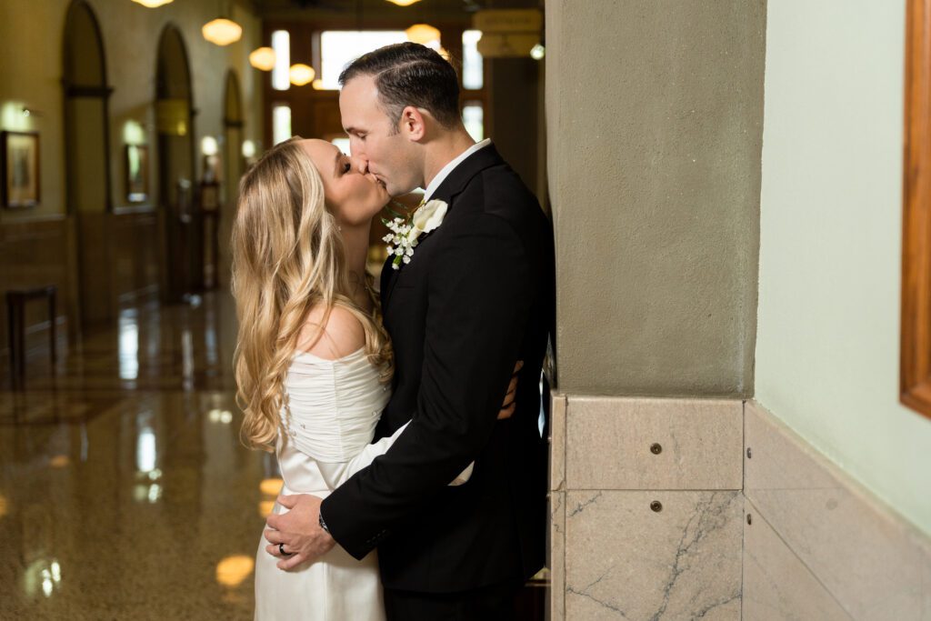 Couple kissing in the arched marble hallway of the Tarrant County Courthouse, captured by Bushel + Peck Photo