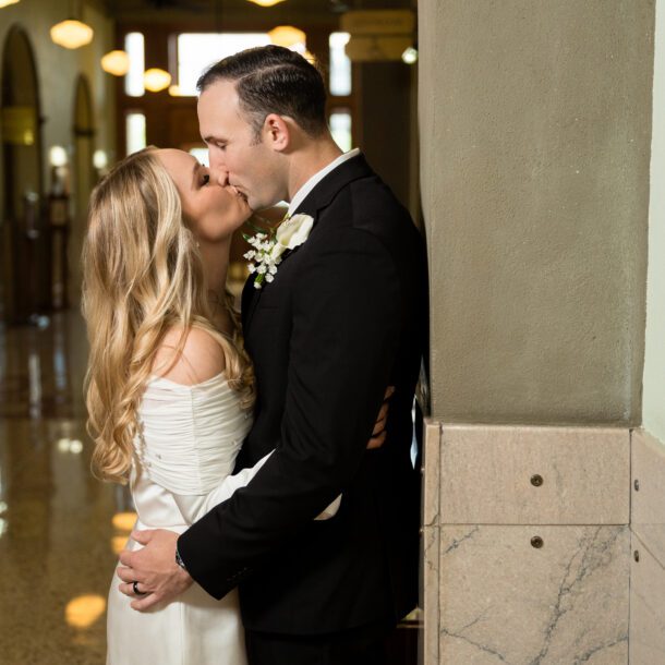 Couple kissing in the arched marble hallway of the Tarrant County Courthouse, captured by Bushel + Peck Photo