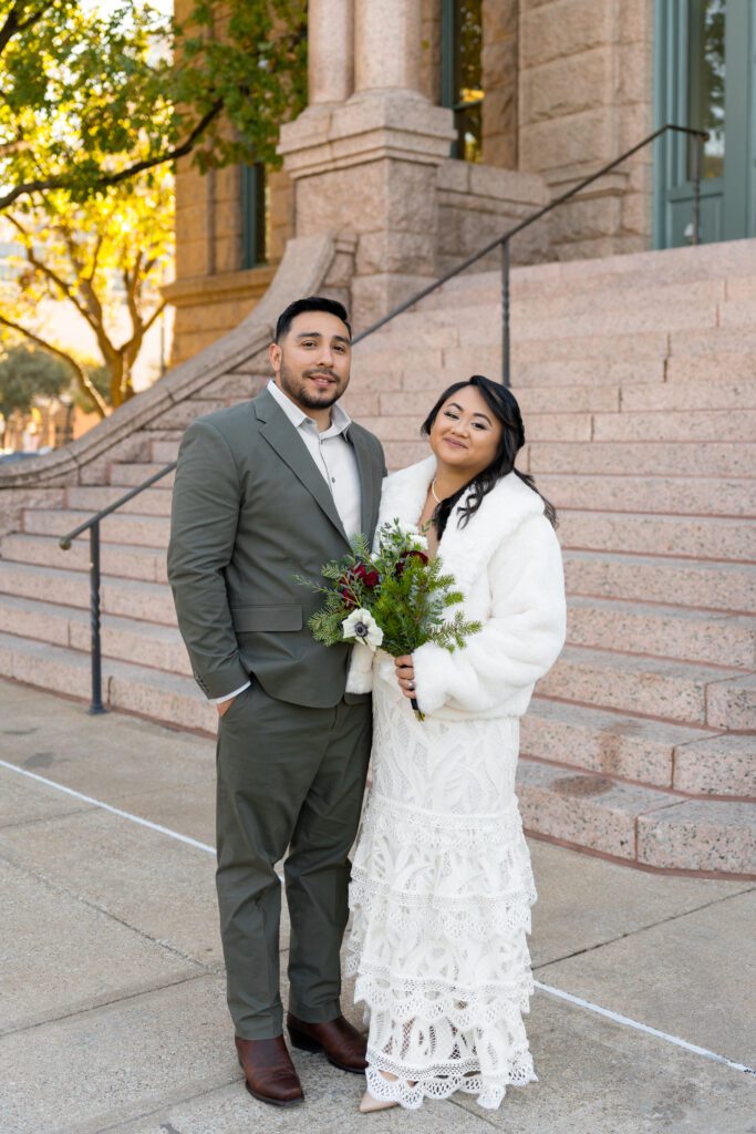 Couple on the pink granite courthouse steps in warm afternoon light in downtown Fort Worth, captured by Bushel + Peck Photo