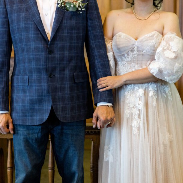 Close-up of the bride and groom holding hands in the Tarrant County courtroom, captured by Bushel + Peck Photo