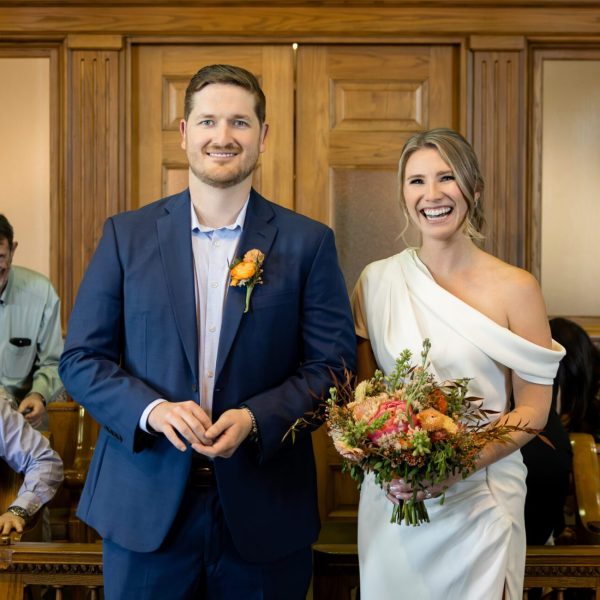Smiling bride and groom standing before the judge during their Tarrant County Courthouse wedding ceremony, captured by Bushel + Peck Photo