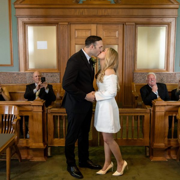 First kiss in the historic courtroom as family applauds at a Fort Worth courthouse wedding, captured by Bushel + Peck Photo